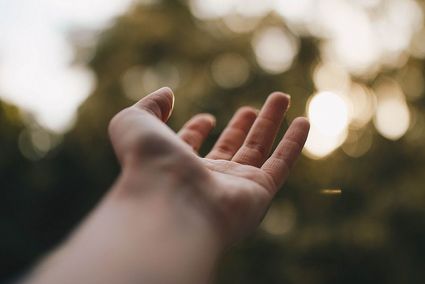 Stock image of a hand reaching up to the sky